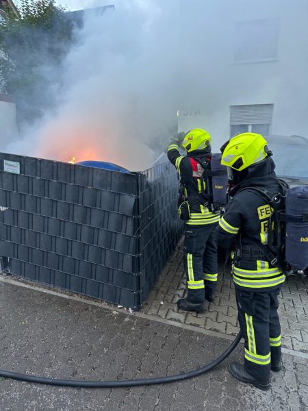 Zwei Einsatzkräfte in Schutzausrüstung bei der Bekämpfung eines Brandes einer Mülltonne